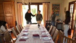 Une salle à manger avec une longue table dressée pour le repas, des chaises en bois et un lustre.