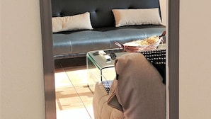 A bedroom with a bed, a nightstand, and a view of a coastal landscape through a large mirror. - 3 room apt. for 2-6 people, sea view, pool, air conditioning; Guadeloupe centre (Le Gosier)
