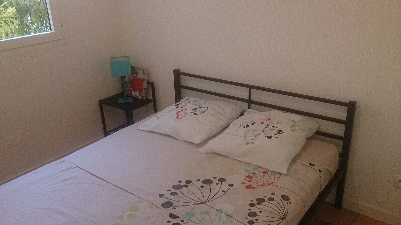 Ein Schlafzimmer mit einem Bett, zwei Kissen, einem Nachttisch und einer Lampe.