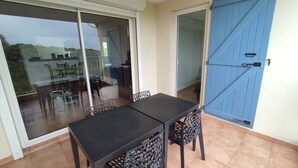 A patio area with a table and chairs, a sliding glass door, and a blue door. - 3 room apt. for 2-6 people, sea view, pool, air conditioning; Guadeloupe centre (Le Gosier)