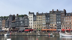 A waterfront with historic buildings, a marina with boats, and outdoor seating areas.