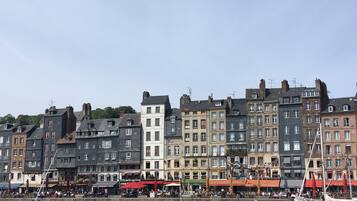 A waterfront with historic buildings, a marina with boats, and outdoor seating for cafes.