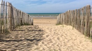 A sandy beach path leading to the ocean, flanked by wooden fences.