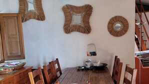 A dining area with a wooden table and chairs, surrounded by white walls with decorative mirrors and a ceiling light. - Small villa located in a quiet pool and sea view / Gulf of Policastro (MARATEA)