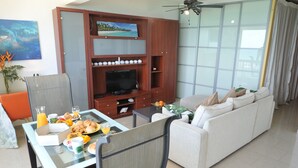 Een moderne woonkamer met een eethoek, een televisie en een groot raam.