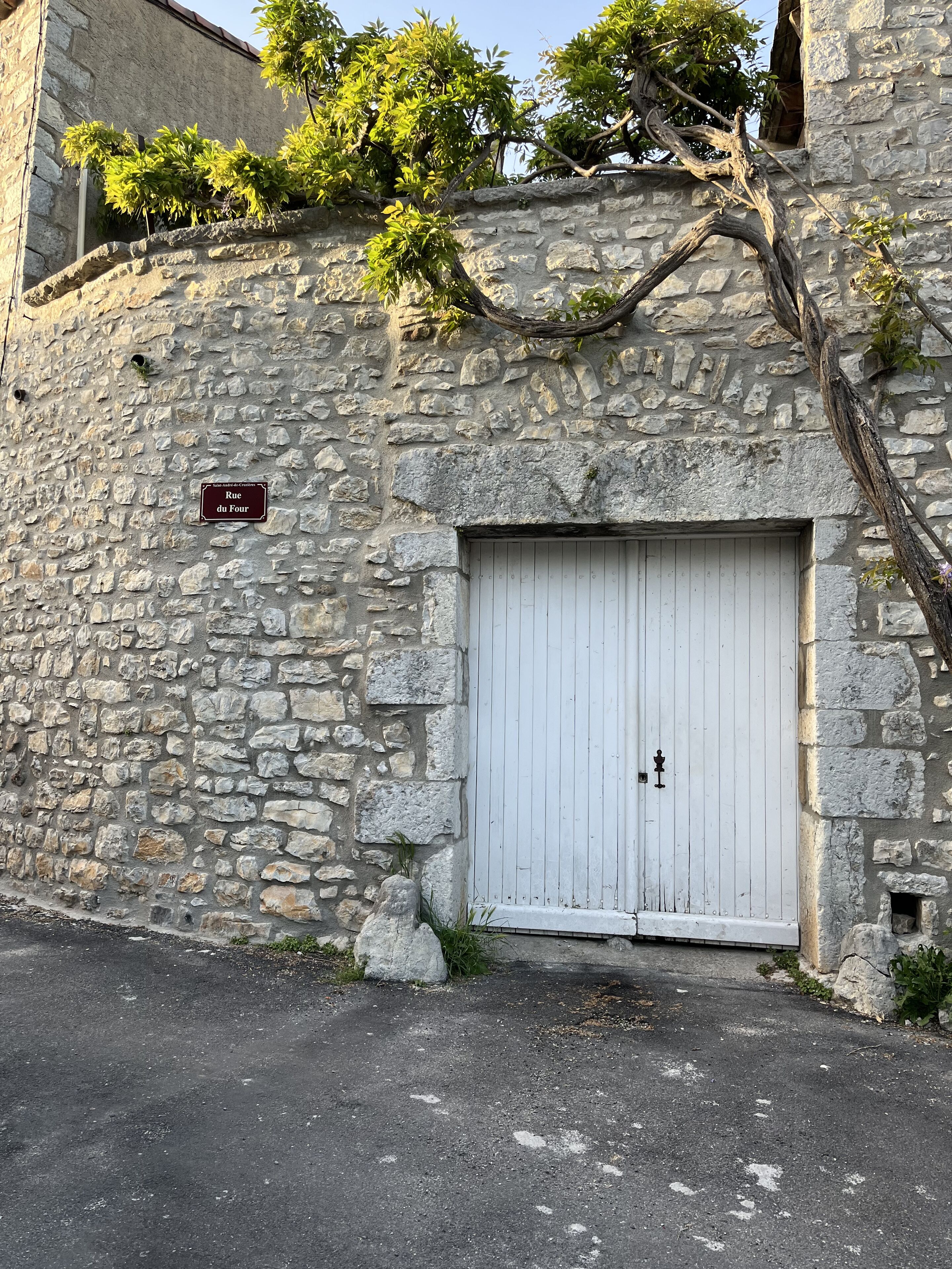 Un muro de piedra con una puerta blanca y un cartel que dice 'Rue du Four'.