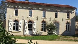 A two-story building with a symmetrical facade, arched windows, and a tiled roof. - Set of houses, with heated indoor pool, surrounded by nature (Le Tablier)