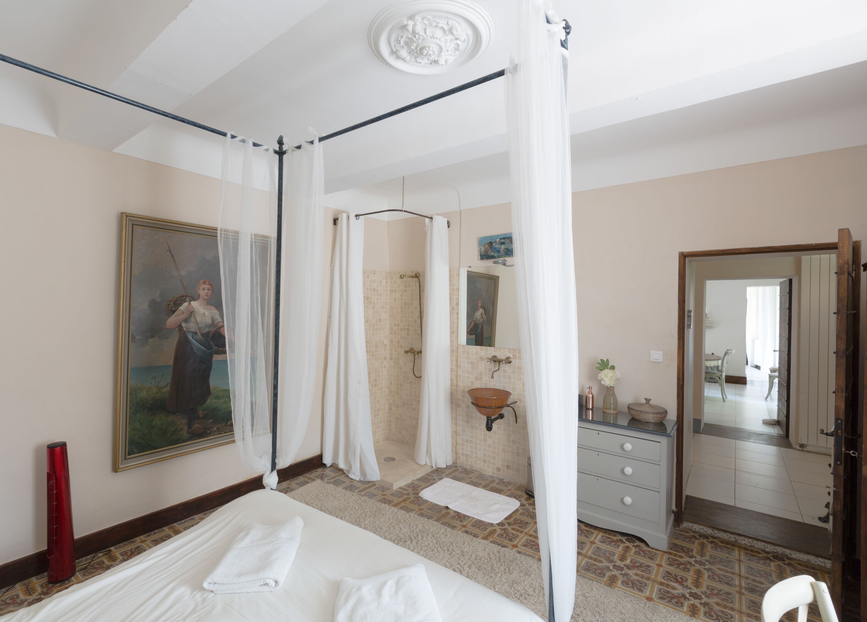 A bedroom with a four-poster bed, a shower, a sink, and a mirror.