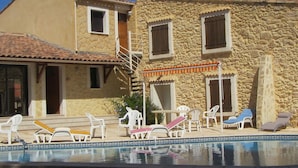 A pool area with lounge chairs and a stone building with a tiled roof. - House near the SEA - private SWIMMING POOL - COUNTRYSIDE - in LANGUEDOC - 15 people (Loupian)