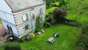 A large, two-story building with a well-maintained garden and outdoor seating area. - "L'école buissonière", a charming family villa between sea and marsh (La Cambe)