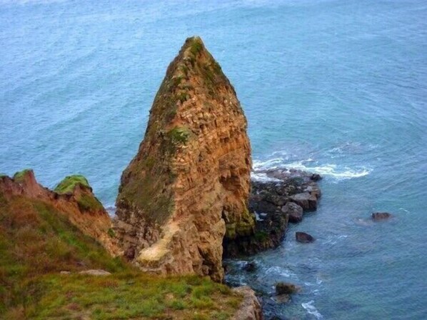 A coastal landscape with a prominent rock formation. - "L'école buissonière", a charming family villa between sea and marsh (La Cambe)