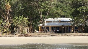 A beachfront property with a two-story building, a sandy beach, and dense vegetation. - Caribbean villa on the beach (LE DIAMANT)