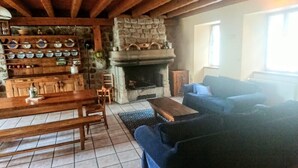 Un salon chaleureux avec une cheminée en pierre, un coin repas avec des meubles en bois et un canapé bleu.