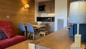 Una cocina moderna con muebles de madera, un comedor con mesa y sillas de madera, y un sofá rojo.