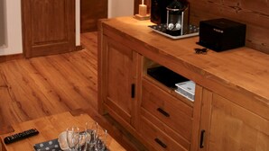 Un armario de madera con un televisor de pantalla plana, una lámpara y una cafetera. Hay una mesa con un control remoto y vasos.