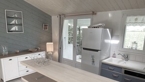Una cocina moderna con una encimera amplia, un refrigerador, un lavamanos y una ventana con vistas a zonas verdes.