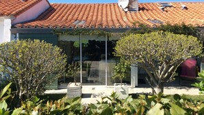 Una casa con techo de tejas, antena parabólica y puerta de cristal.