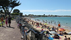 Una playa con gente, bicicletas y sombrillas.
