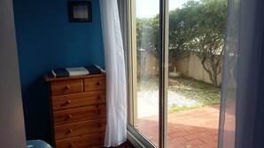 A room with a wooden dresser, a window with a view of a garden and a tree. - LARGE 3 BEDROOM APARTMENT ON THE SEAFRONT in quiet Barcarès just off the beach (Le Barcarès)