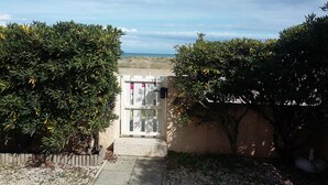 A gated entrance with a view of the ocean, surrounded by dense foliage. - LARGE 3 BEDROOM APARTMENT ON THE SEAFRONT in quiet Barcarès just off the beach (Le Barcarès)