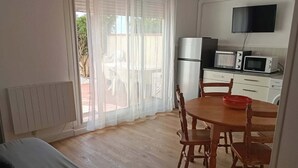 A compact kitchen with a refrigerator, microwave, and a dining table with chairs. - LARGE 3 BEDROOM APARTMENT ON THE SEAFRONT in quiet Barcarès just off the beach (Le Barcarès)