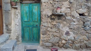 A rustic stone building with a green door, a ceramic sign, and a small shelf with a potted plant. - Villa, near Ile Rousse and the sea, lake and mountain view (Santa-Reparata-Di-Balagna)