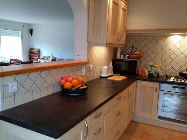 A kitchen with a wooden countertop, a bowl of fruit, a toaster, a microwave, and a stove. - Villa, near Ile Rousse and the sea, lake and mountain view (Santa-Reparata-Di-Balagna)