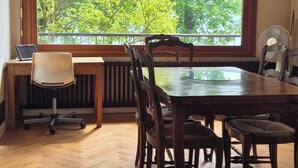 Ein Essbereich mit großem Fenster, Holzboden und einem Tisch mit Stühlen.