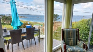Ein Zimmer mit Meerblick, einem Esstisch mit Stühlen und einem gemusterten Sessel.
