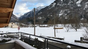 Paisaje montañoso nevado con un balcón de madera que da a una zona residencial.