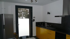 Una cocina con armarios amarillos, encimera negra y refrigerador de acero inoxidable.