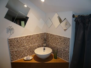 Un baño con lavamanos blanco, espejo y salpicadero de mosaicos.