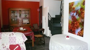 Un comedor con una mesa roja, sillas y un armario con puertas de cristal.