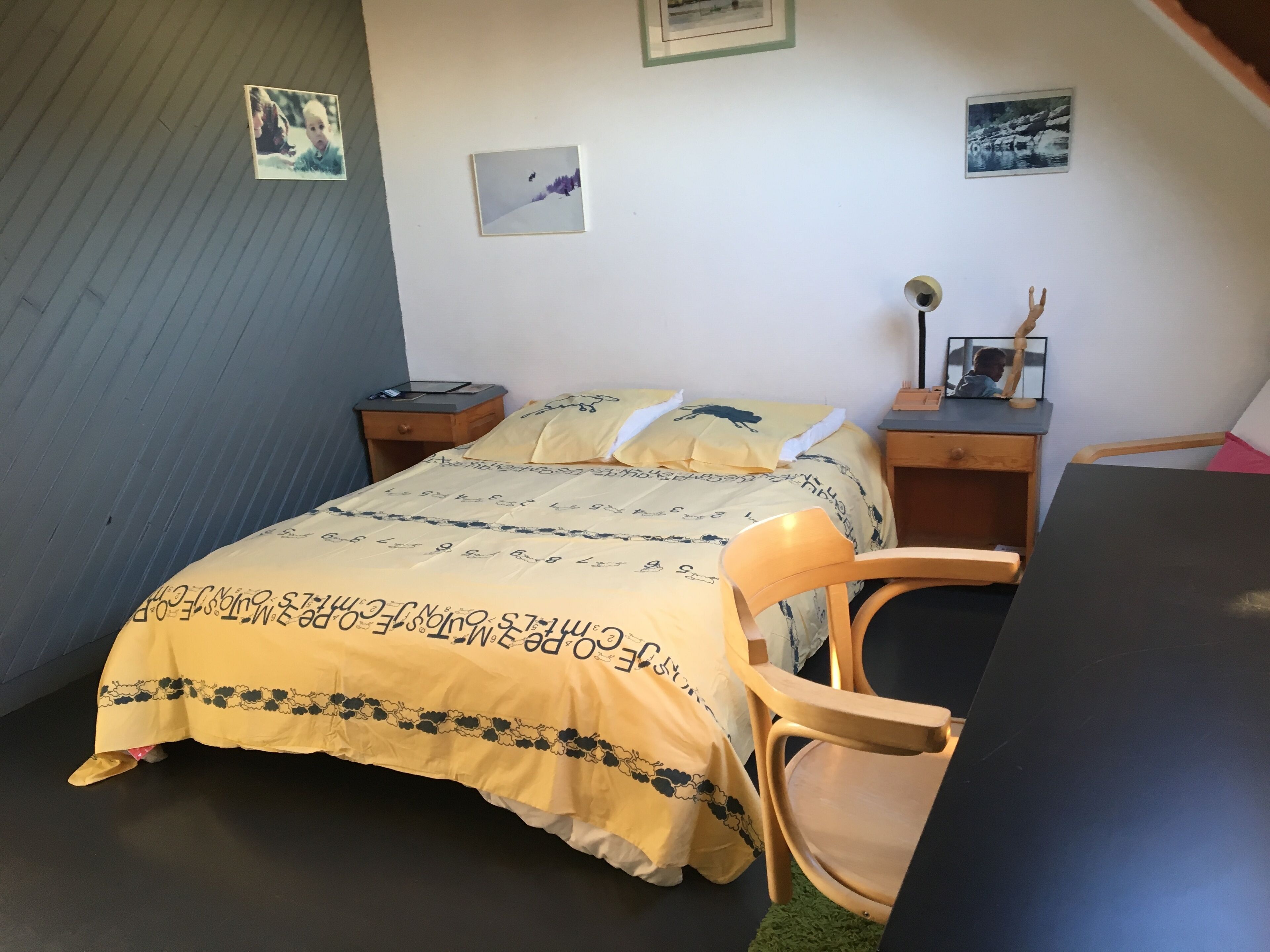 A bedroom with a bed, a chair, a desk, and a nightstand.