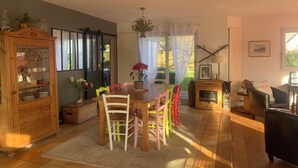A cozy living room with a wooden dining table, colorful chairs, a fireplace, and a cabinet with glass doors. - Detached family home south brittany less than 200 m from the beach  (Larmor-Plage)