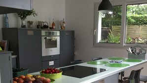 A modern kitchen with a central island, a built-in oven, and a window with a view of greenery. - Detached family home south brittany less than 200 m from the beach  (Larmor-Plage)
