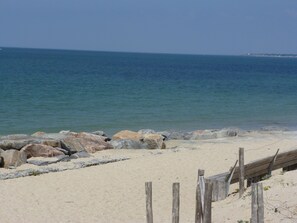 Ein Strand mit einer Holzzaun und großen Felsen im Vordergrund.