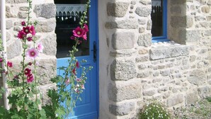 Ein Steinhaus mit einer blauen Tür und einem kleinen Fenster.