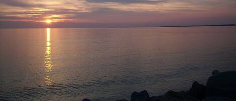 A sunset over a calm sea with a distant shoreline.