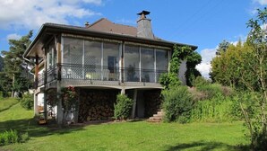 A two-story house with a balcony, surrounded by a grassy yard and trees. - Spacious 3-star house in the Vosges (Nayemont-Les-Fosses)