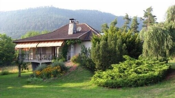 A house with a sloped roof, a chimney, and a porch with a railing. - Spacious 3-star house in the Vosges (Nayemont-Les-Fosses)