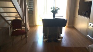 A staircase leading to a landing with a red chair and a dining table with chairs.