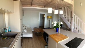 A modern kitchen with a central island, a dining area with a sofa, and a staircase leading to another level.