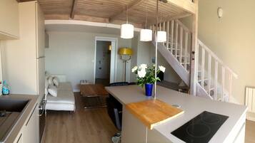 A modern kitchen with a central island, a dining area with a sofa, and a staircase leading to another level.