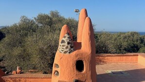 Eine terrakotta-Skulptur mit Steinoptik auf einer Dachterrassen mit freiem Blick auf das Meer.