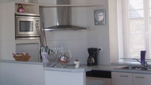 Una cocina con campana de acero inoxidable, microondas, cafetera y un reloj en la pared.