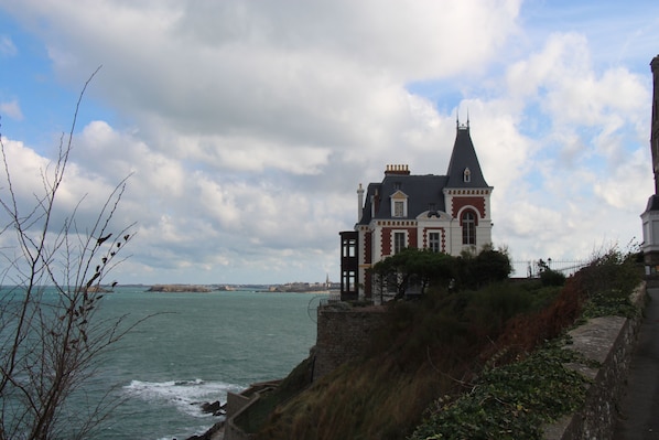 Una casa costera con una torre destacada, ubicada en un acantilado con vistas al mar.