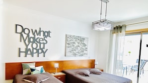 A hotel room with two beds, a wooden headboard, a motivational wall art, a fish illustration, and a view of the outside. - Ideal location, 20 m from the beach, in central Algarve, Albufeira (Albufeira)