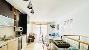 A modern kitchen with a dining area, a TV mounted on the wall, and a view of the outdoors. - Ideal location, 20 m from the beach, in central Algarve, Albufeira (Albufeira)
