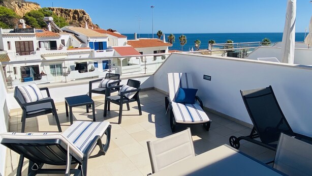 A rooftop terrace with lounge chairs and tables, overlooking a coastal area with buildings and a clear sky. - Ideal location, 20 m from the beach, in central Algarve, Albufeira (Albufeira)